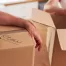 Fatboy Slims Moving Company | Blog Two people packing boxes, one writing "KITCHEN" on a box with a marker, while the other handles a metal pot.