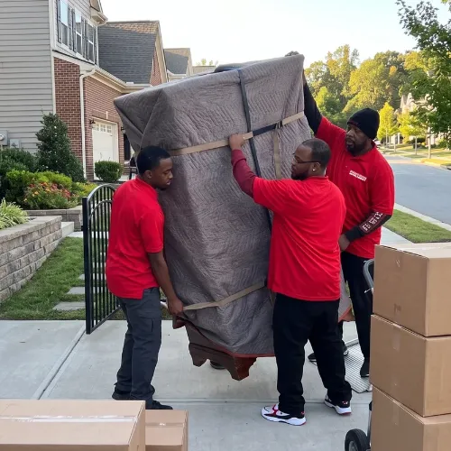 Fatboy Slims Moving Company crew carrying a large wrapped furniture piece.