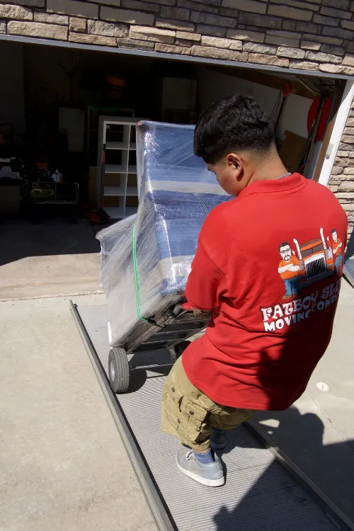 Fatboy Slims Moving Company mover carefully handling wrapped furniture during a move.