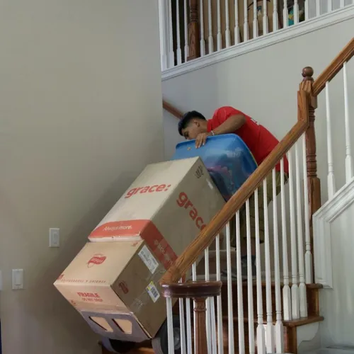 Fatboy Slims Moving Company mover carrying a large boxed item down a staircase.