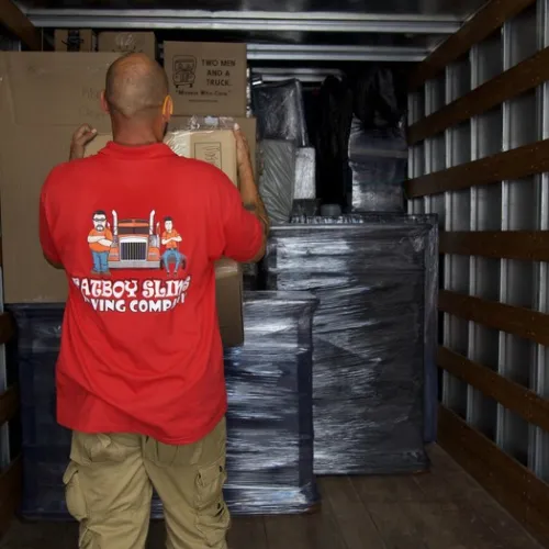 Fatboy Slims Moving Company mover organizing wrapped furniture and boxes inside a moving truck.