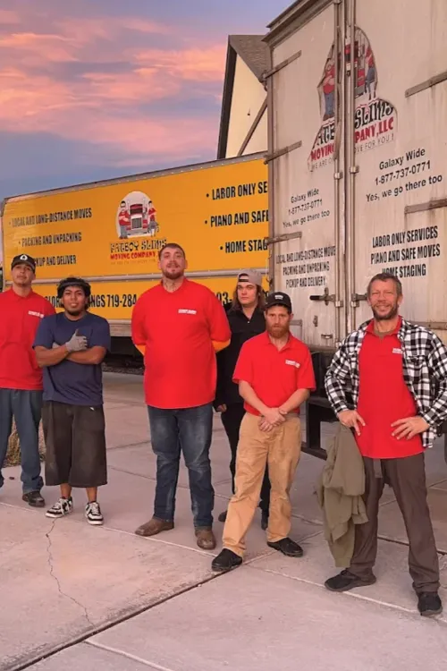 Fatboy Slims Moving Company team standing together beside branded moving trucks.
