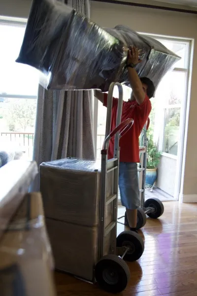 Fatboy Slims Moving Company mover carefully handling wrapped furniture.