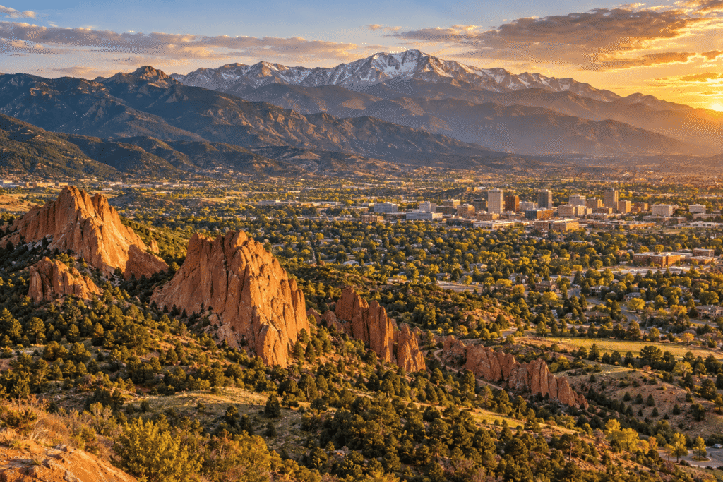 Aerial view of Colorado Springs at golden hour with Garden of the Gods red rock formations and Pikes Peak